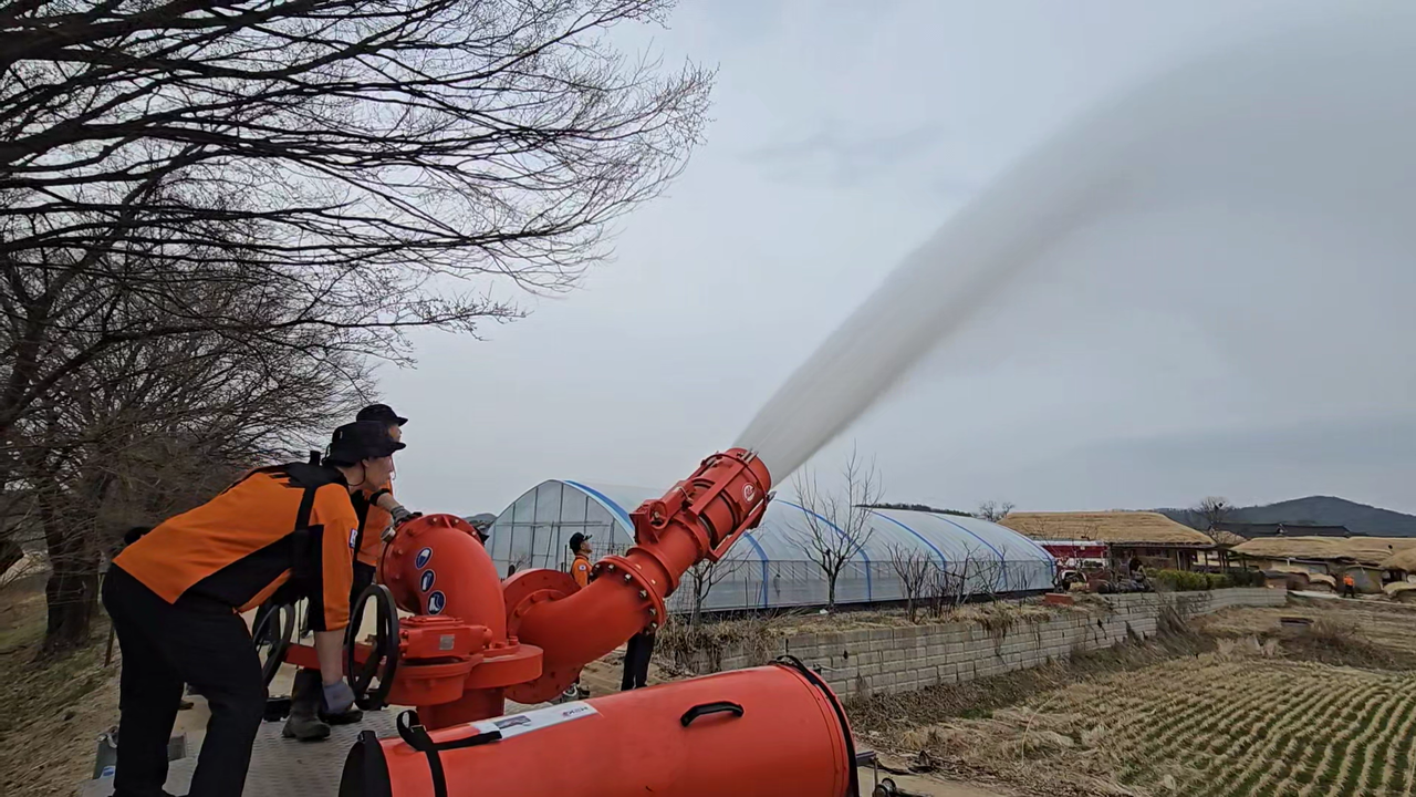 Firefighters use a high-capacity water spray system to soak parts of Hahoe Village in Andong, North Gyeongsang Province, on Thursday. (National Fire Agency)