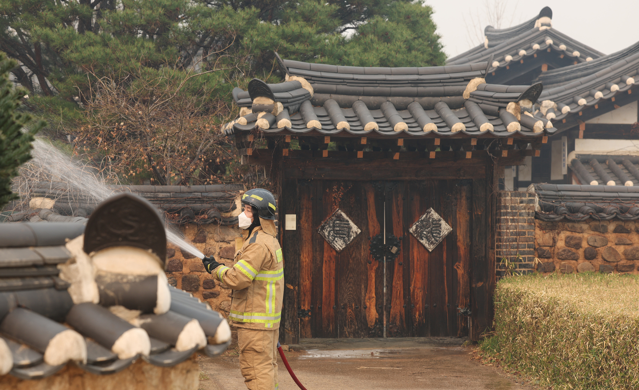 A firefighter sprays water on a hanok, or Korean traditional house, at Hahoe Village in Andong, North Gyeongsang Province, on Wednesday. (Yonhap)