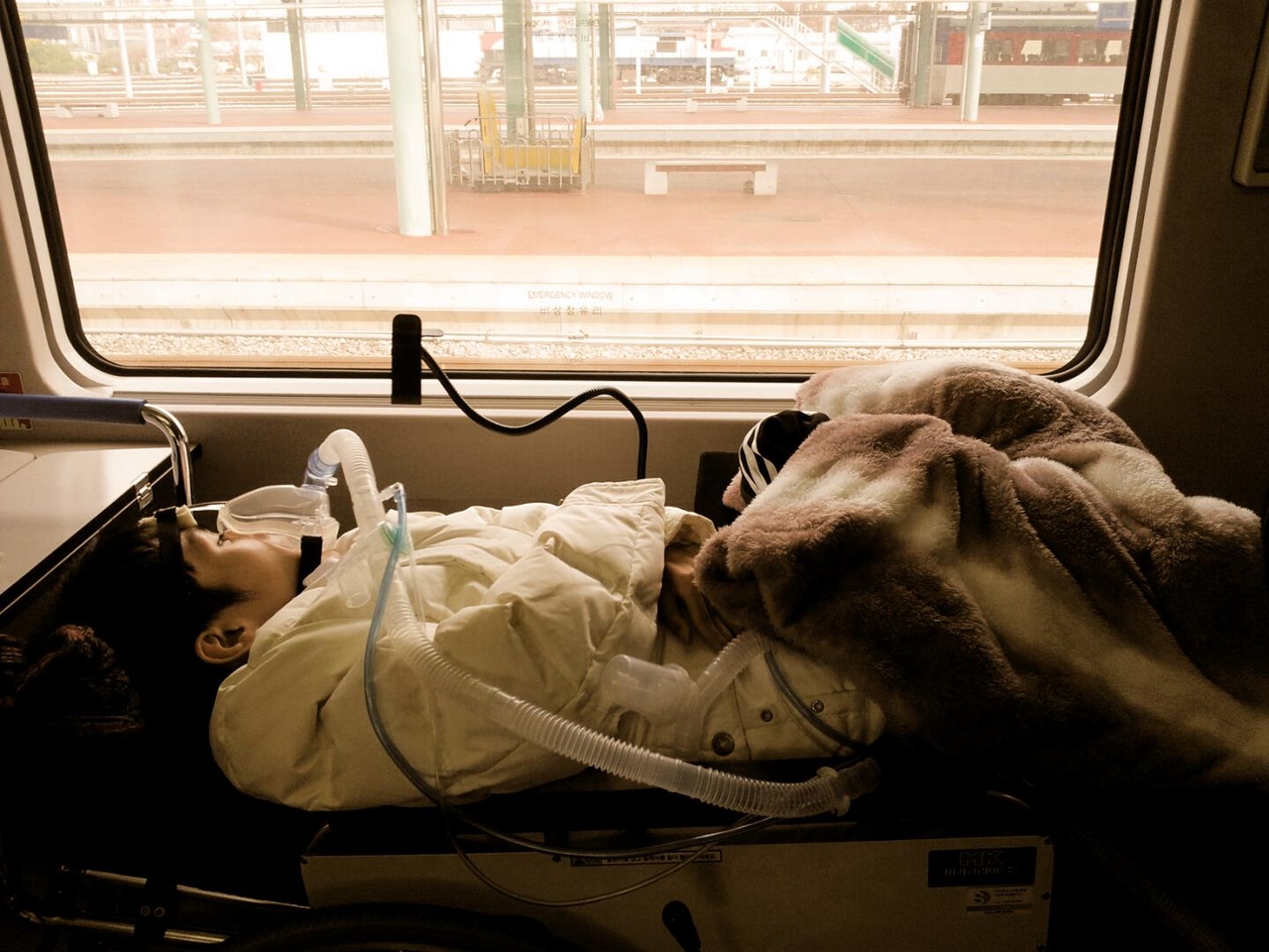 Determined to explore the world despite his physical limitations, Jang Ik-seon traveled to Japan in 2019, lying on a stretcher secured across six seats, with his ventilator and essential equipment carefully set up for the journey. (Courtesy of Jang Ik-seon)