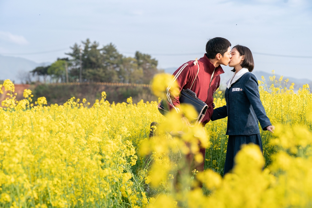 드라마 ‘폭싹 속았수다’의 한 장면으로 주인공인 애순(아이유)과 관식(박보검)이 제주도 유채꽃밭을 배경으로 첫 키스를 하고 있다.  [넷플릭스 제공]