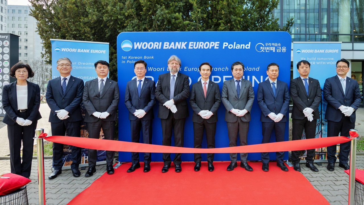 Ryu Hyung-jin (sixth from left), head of Woori Bank's global group, and Lee Jung-woo (far right), manager of Woori Bank's Poland branch, pose for a photo with key executives from local businesses and government representatives at the branch's inauguration ceremony in Warsaw, Poland, on Monday. (Woori Bank)