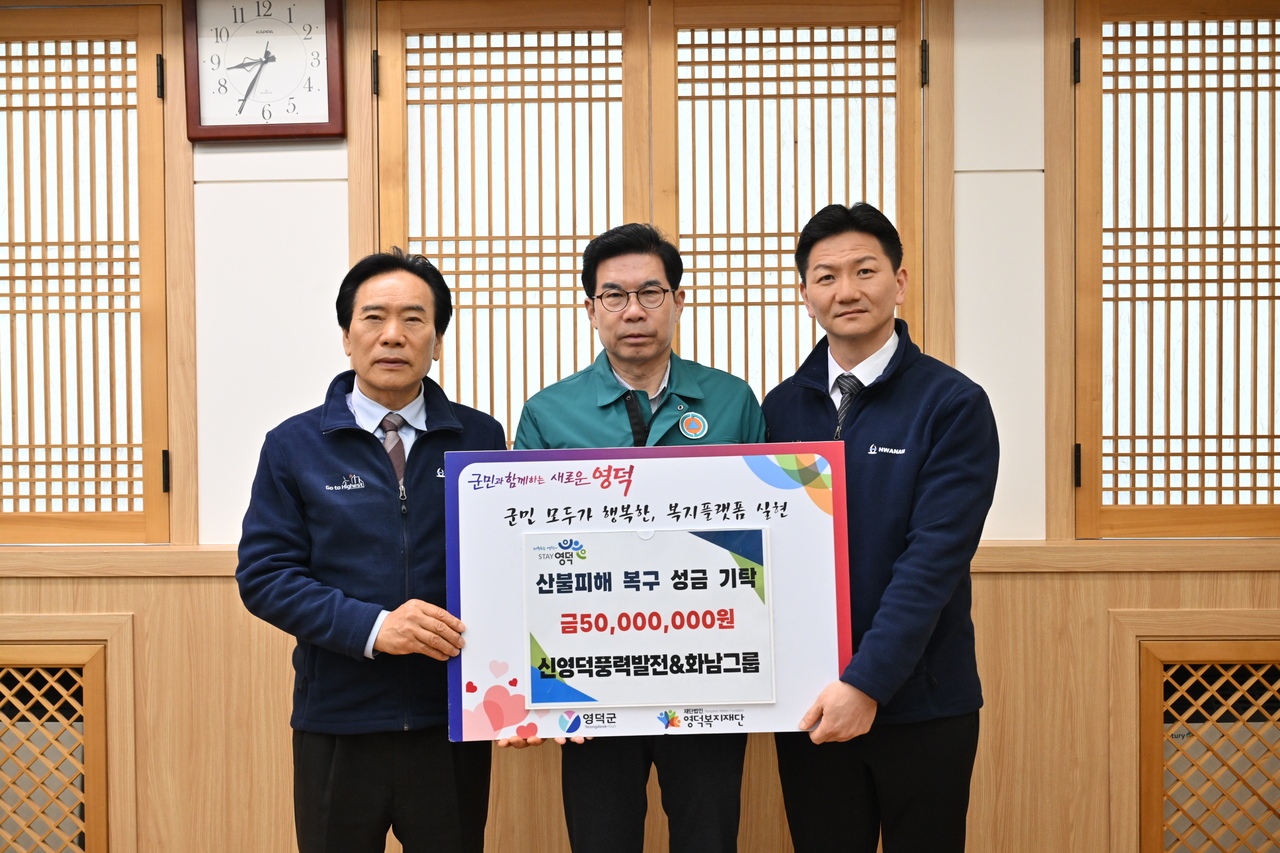 신영덕풍력발전·화남그룹의 박몽용 대표(왼쪽)가 김광열 영덕군수에게 성금을 전달하고 있다.[영덕군 제공]