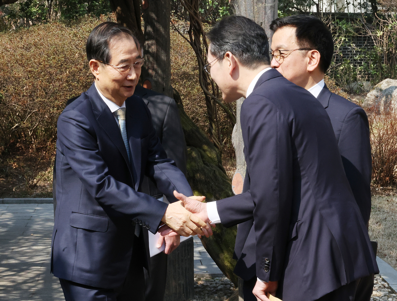 Acting President and Prime Minister Han Duck-soo (left) shakes hands with Samsung Electronics Executive Chairman Lee Jae-yong (second from left) before a meeting on economic security strategy at his official residence in Seoul on Tuesday. (Yonhap)