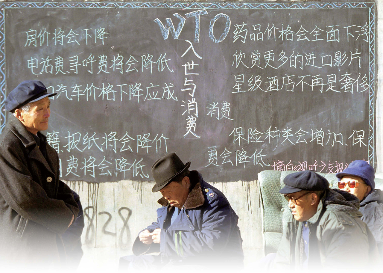 중국의 세계무역기구(WTO) 가입을 사흘 앞둔 2001년 12월 8일, 베이징 근처에서 세 명의 노인이 WTO 회원국이 되면 얻을 수 있는 이점을 설명하는 칠판 앞에서 쉬고 있다. 칠판엔 주택, 자동차, 호텔 등의 요금이 인하된다는 내용이 적혀 있다. [게티이미지]