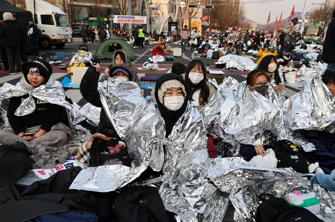 Participants of a 24-hour overnight protest calling for the impeachment of President Yoon Suk Yeol are seen wearing thermal blankets near Anguk Station in Seoul on Wednesday. (Yonhap)