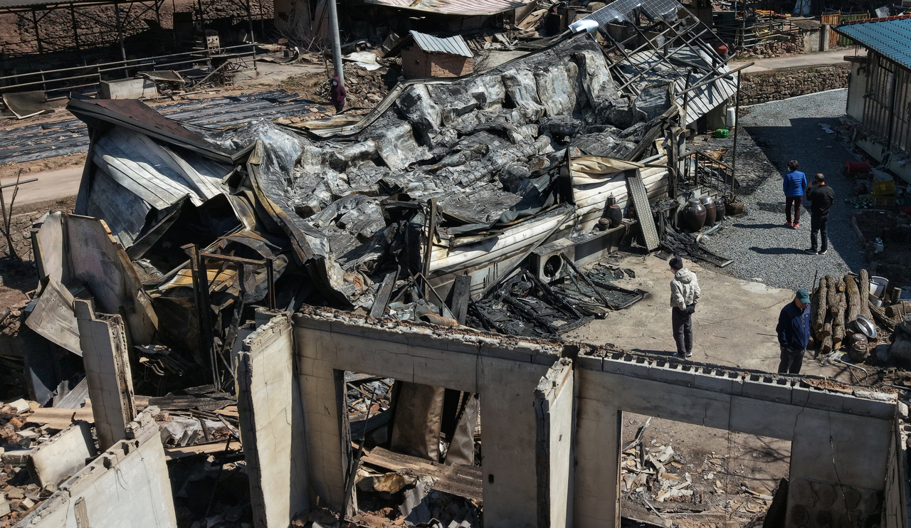 Residents affected by the wildfires inspect a home burned down to ashes at Andong, North Gyeongsang Province, Sunday. (Newsis)