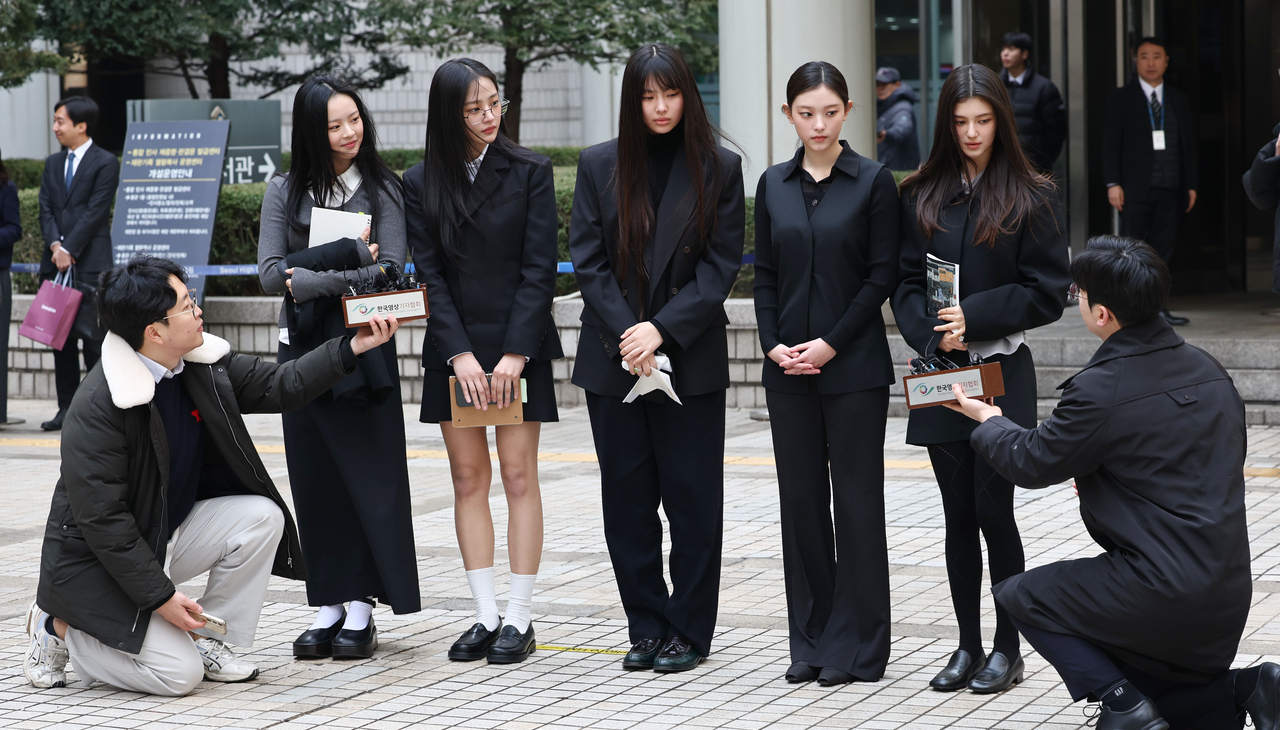 The bandmates of NewJeans respond to reporters' questions as they leave the Seoul Central District Court on March 7. They appeared for a hearing on Ador’s injunction request filed in January to maintain management rights over the group and prevent them from independently signing advertising contracts. (Yonhap)