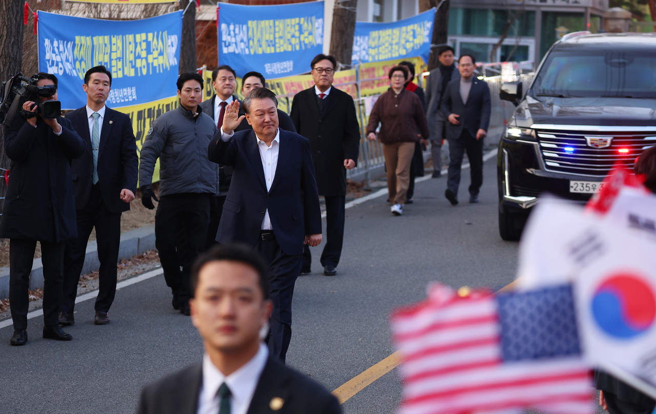 President Yoon Suk Yeol steps out of his security vehicle and greets supporters as he walks outside Seoul Detention Center in Uiwang, Gyeonggi Province, March 8. (Yonhap)