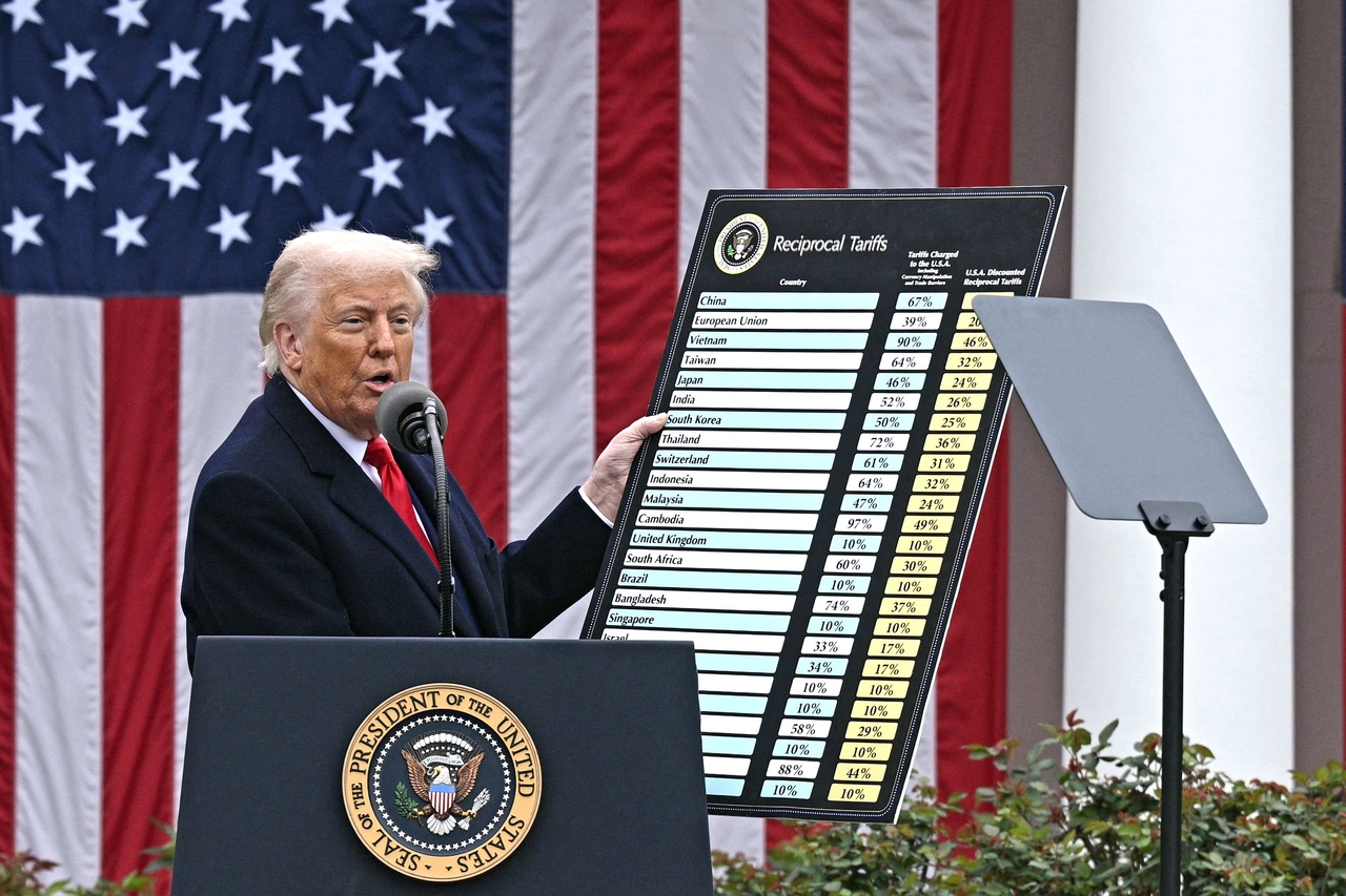 US President Donald Trump delivers remarks on reciprocal tariffs as US Secretary of Commerce Howard Lutnick holds a chart during an event in the Rose Garden entitled "Make America Wealthy Again" at the White House in Washington, DC, on April Wednesday. (AFP-Yonhap)