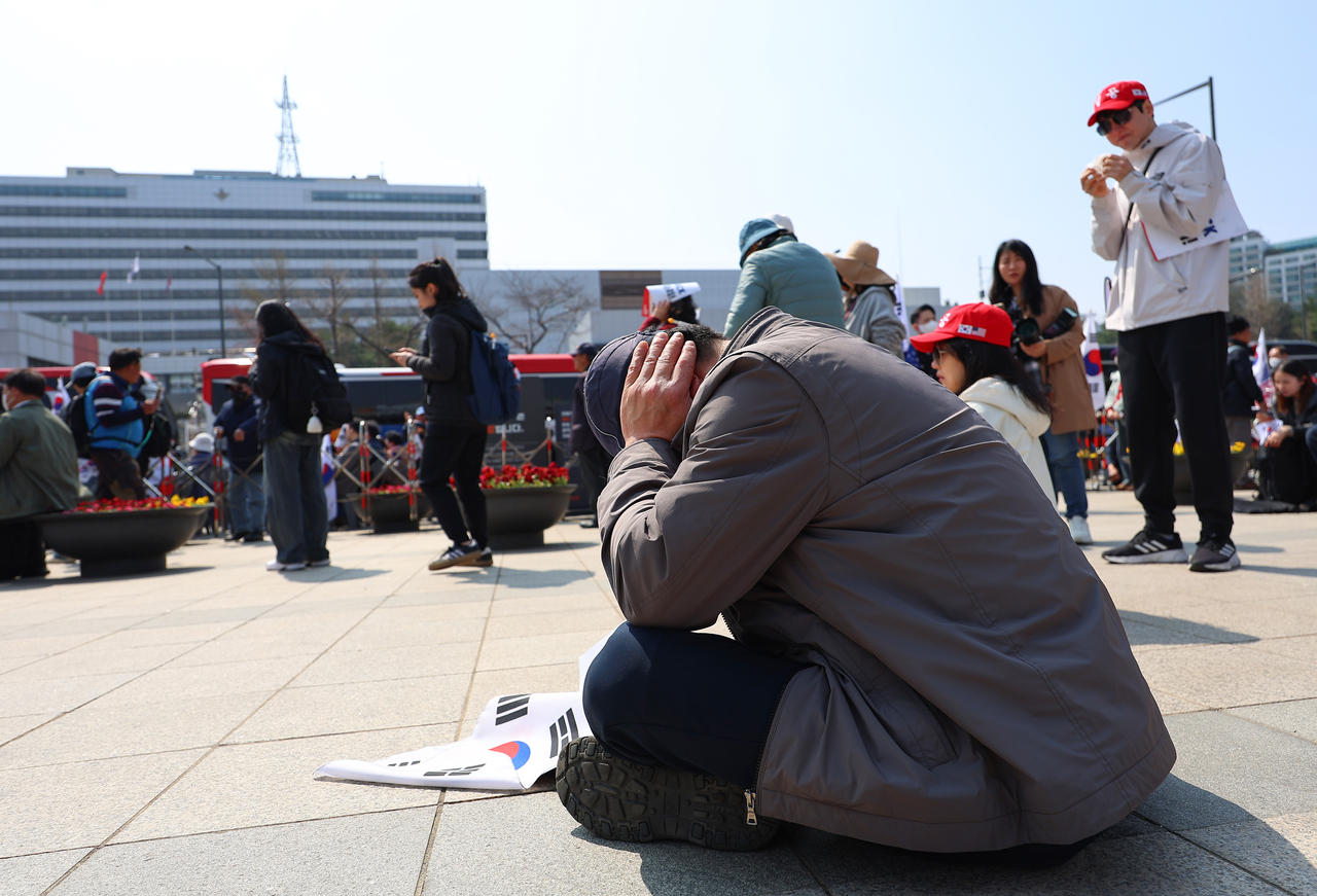 A supporter bows their head near the presidential office in Yongsan, Seoul, on Friday after the Constitutional Court announced its decision to uphold the impeachment of former President Yoon Suk-yeol. (Yonhap)