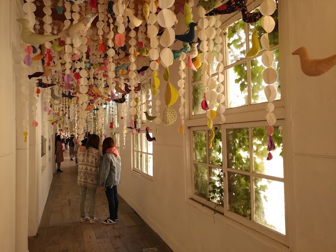 Visitors take photos in a hallway where installation artworks hang from the ceiling. (Ami Art Museum)