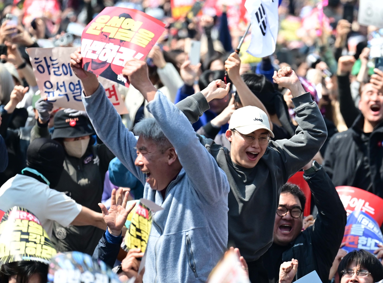 Protesters calling for the Constitutional Court to remove impeached President Yoon Suk Yeol express joy at the verdict near Anguk Station in central Seoul, Friday. (Lee Sang-sub/The Korea Herald)