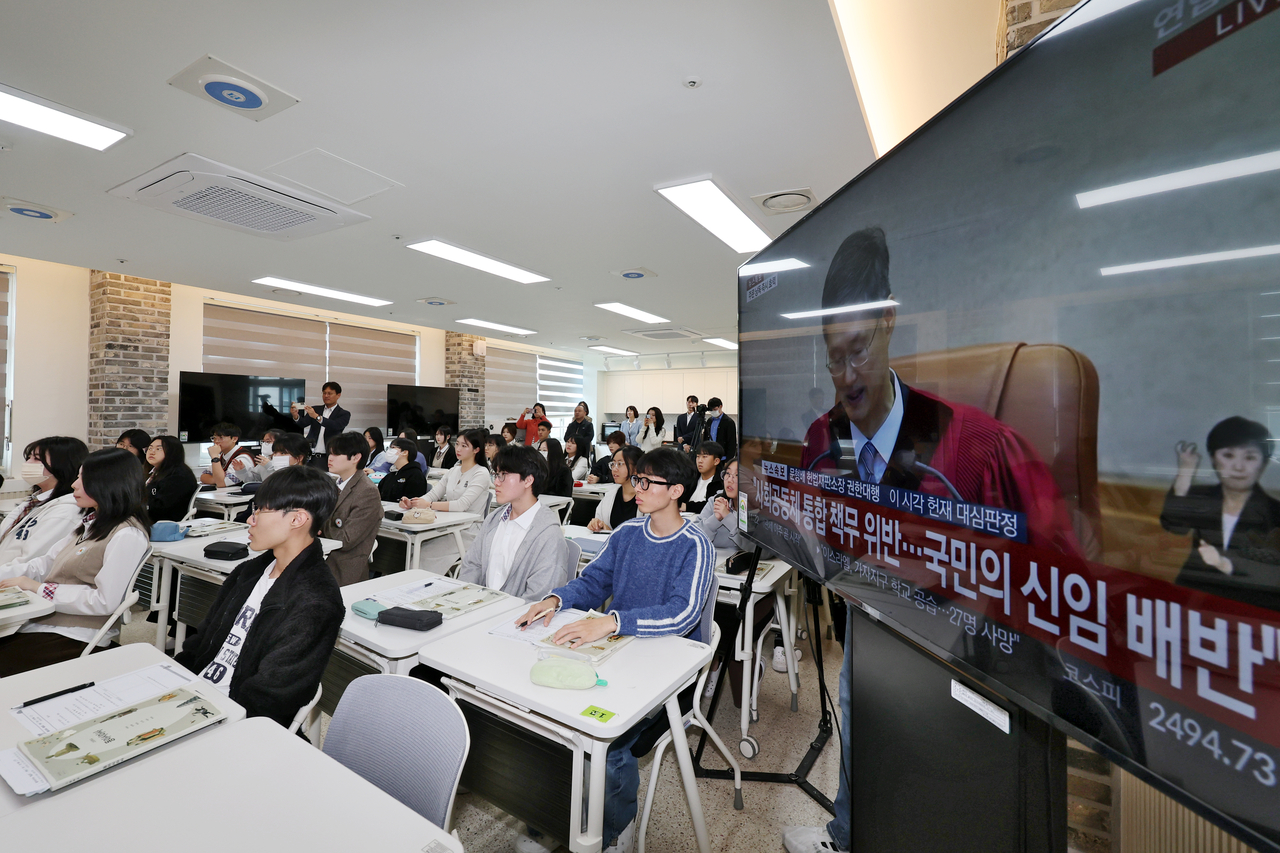 High school students in a Gwangju classroom watch the live broadcast of the Yoon Suk Yeol impeachment ruling on TV on Friday. (Yonhap)