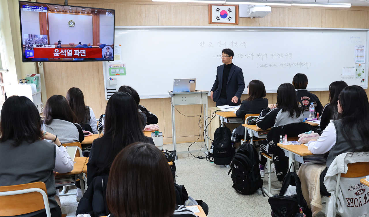High school students and a teacher in a classroom in Incheon watch the live broadcast of the Yoon Suk Yeol impeachment ruling on TV on Friday. (Yonhap)