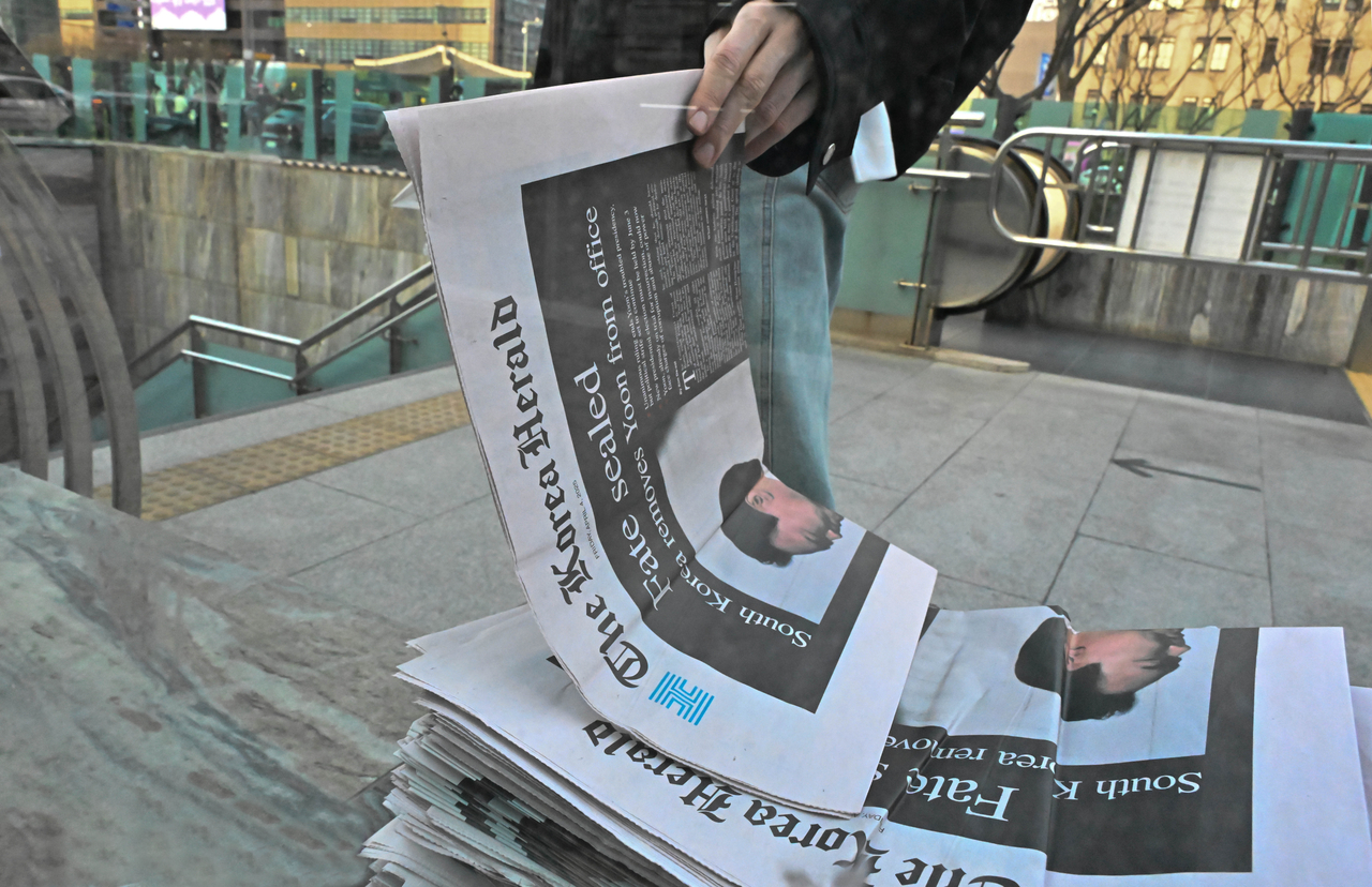 A pedestrian takes The Korea Herald extra edition at Gwanghwamun Square in Jongno-gu, Seoul, Friday. (Lee Sang-sup/The Korea Herald)