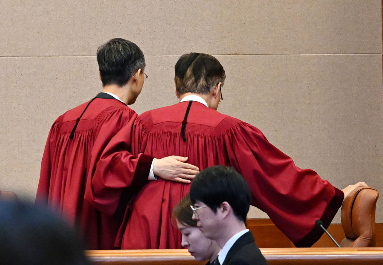 Constitutional Court of Korea acting Chief Justice Moon Hyung-bae (left) leaves the courtroom with Justice Kim Hyung-du after delivering a unanimous verdict upholding the impeachment of former President Yoon Suk Yeol on Friday. (Yonhap)