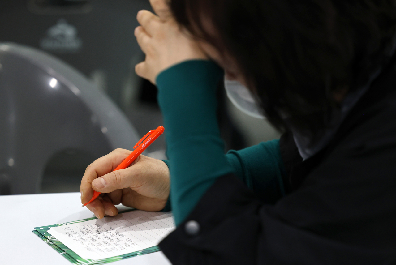 A bereaved family member writes a letter in memory of a victim of the Jeju Air crash at Muan International Airport. (Yonhap)