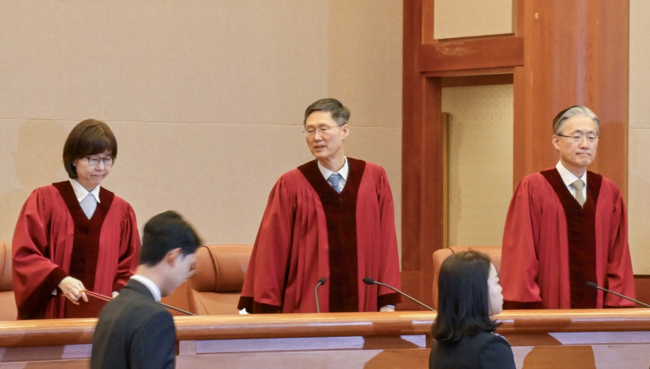 The Constitutional Court of Korea Justice Lee Mi-son (left) and acting Chief Justice Moon Hyung-bae (center) enter the courtroom for a verdict announcement in Seoul. (Yonhap)