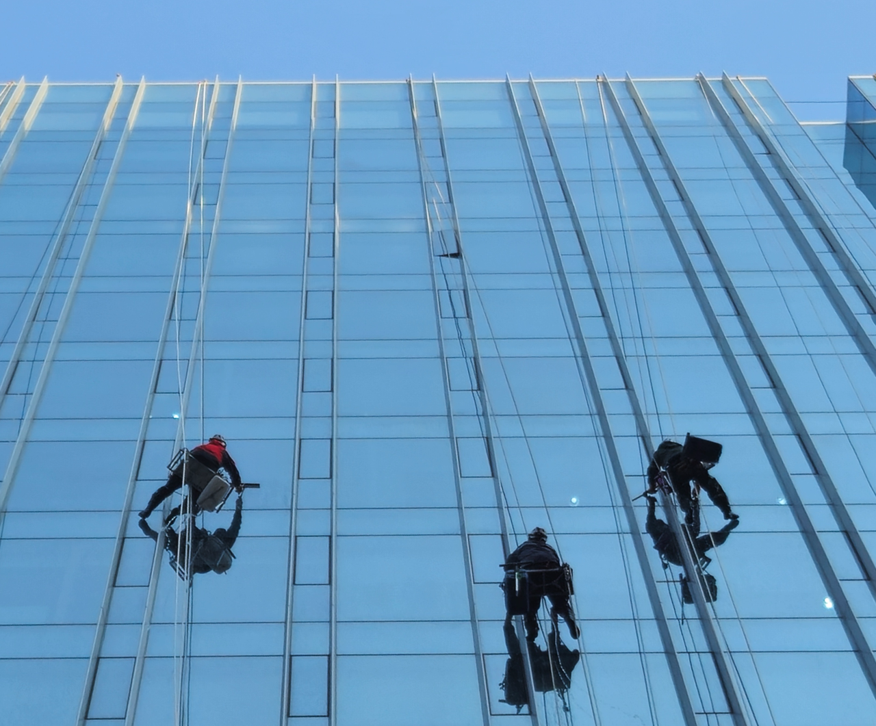 Suspended by ropes, workers clean the exterior facade of a high-rise building in Jongno-gu, Seoul, on Monday. (Yonhap)