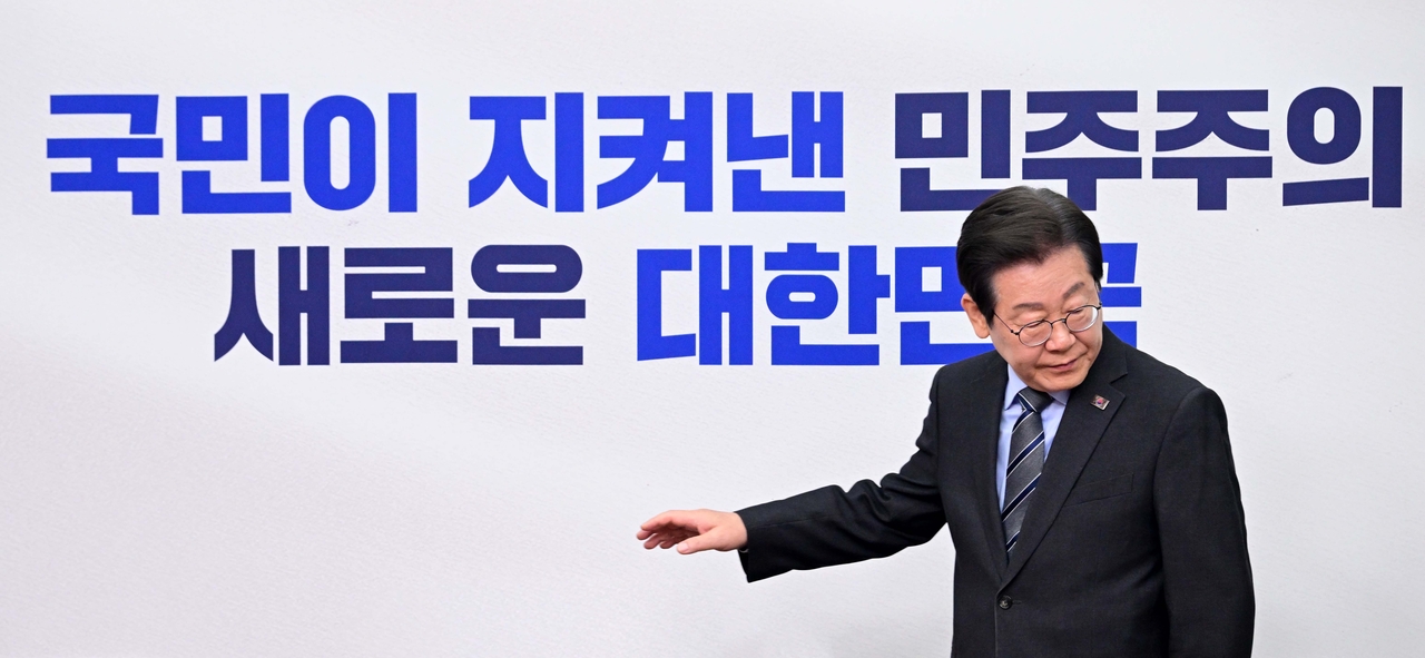 Democratic Party of Korea leader Rep. Lee Jae-myung walks in front of a banner at a party leadership meeting on Monday. The banner behind him reads: "Democracy saved by the people; a new Republic of Korea." (Lee Sang-sub/The Korea Herald)