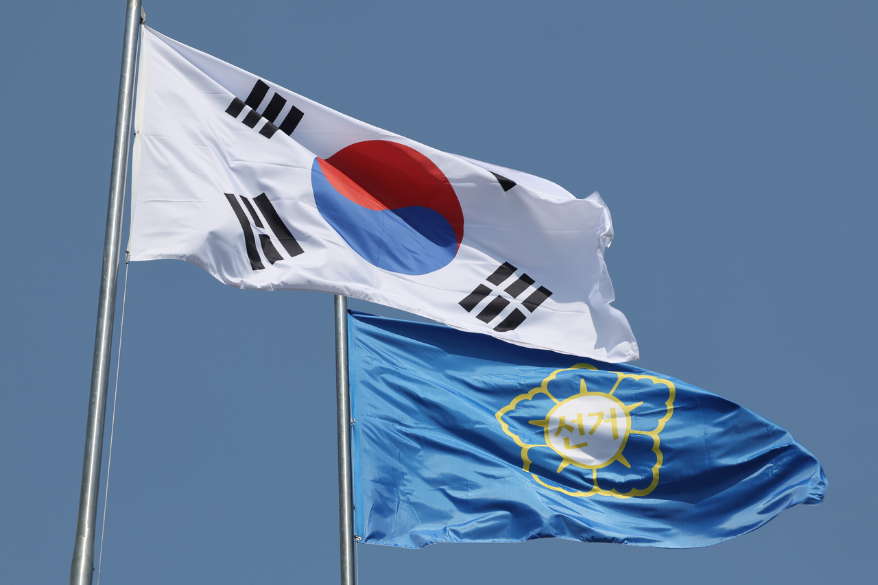 South Korea's national flag (left) and a flag representing election authorities are seen in a photo taken near the National Election Commission headquarters in Gwacheon, Gyeonggi Province, Sunday. (Yonhap)