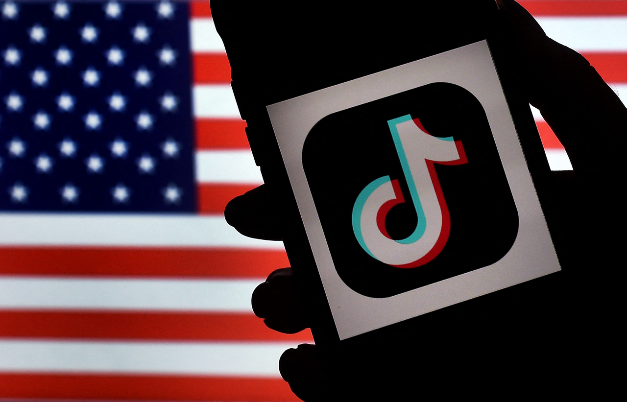 The social media application logo, TikTok is displayed on the screen of an iPhone on an American flag background. AFP-Yonhap