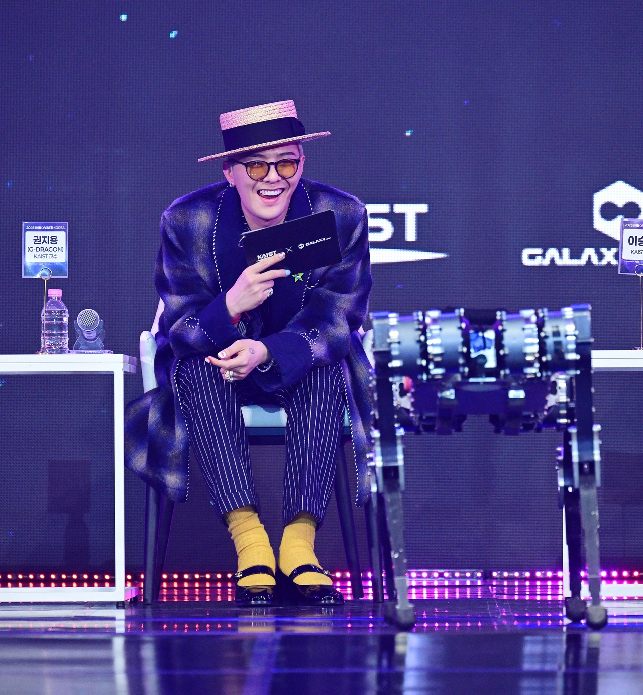 G-Dragon observes a robot dance to his must at the "Innovate Korea 2025" forum held at KAIST in Daejeon on Wednesday. (Lee Sang-sup/The Korea Herald)