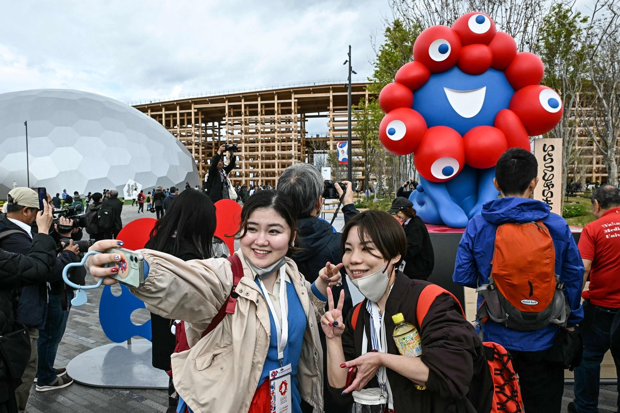 People pose for a photo in front of "Myaku-Myaku," the mascot of the 2025 Osaka Expo, as the gates open to the public on the first day of the six-month 2025 Osaka Expo in the city of Osaka on April 13, Sunday. (AFP-Yonhap)