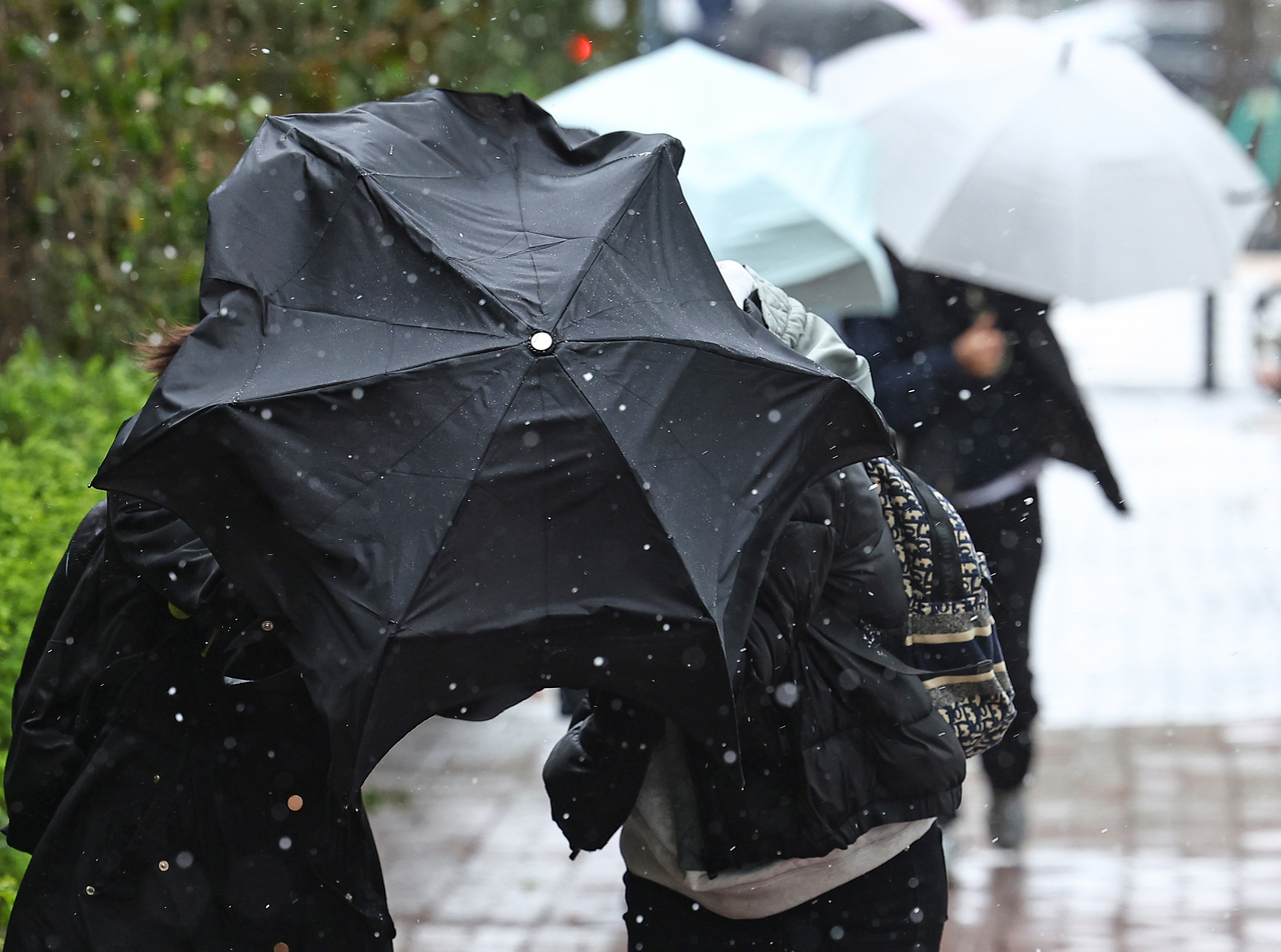 Pedestrians shield themselves with their umbrellas as strong winds and hail sweep through Seocho-gu, Seoul, on Sunday. (Yonhap)