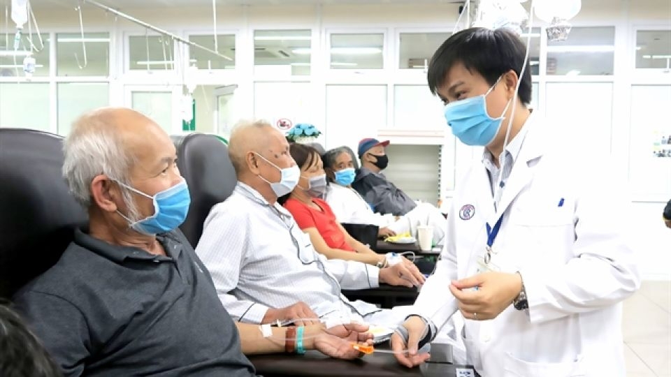 Department Director Le Minh Hien (right) talks to an elderly patient about his health and family situation.   (Viet Nam News)