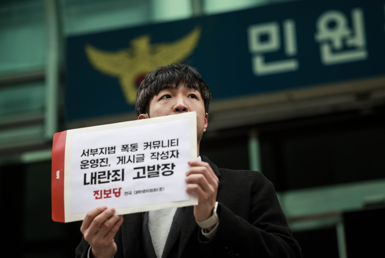 Progressive Party youth leader Park Tae-hoon holds a sign outside the National Police Agency in Seoul on Jan. 31, calling for criminal charges against online forum operators and users linked to planning the violent Jan. 19 mob attack on Seoul Western District Court. (Progressive Party)