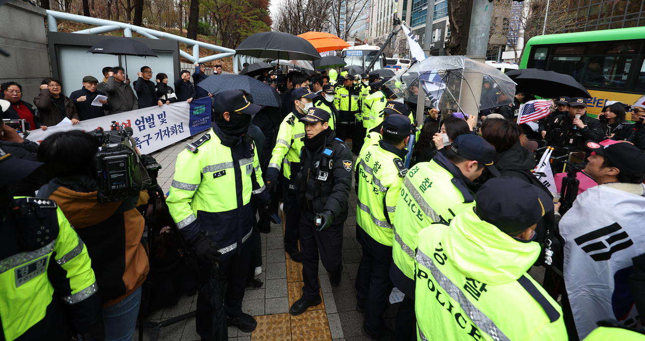 내란 우두머리 혐의로 기소된 윤석열 전 대통령의 첫 형사재판이 열린 14일 서울 서초구 서울중앙지방법원 앞에서 경찰 관계자들이 윤 전 대통령 엄벌 촉구 기자회견을 하는 시민단체와 윤 전 대통령 지지자들을 분리하고 있다. [연합]