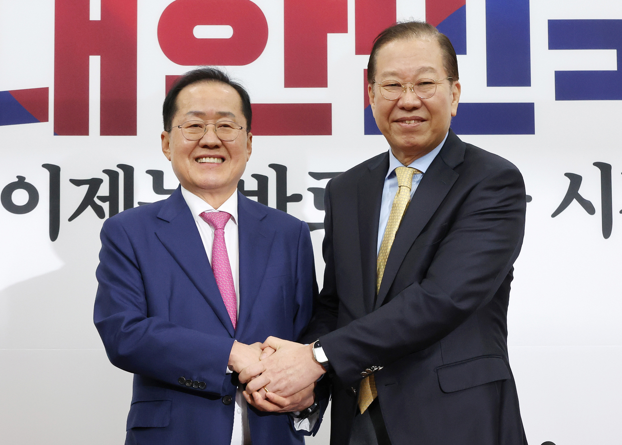 Former Daegu Mayor Hong Joon-pyo (left) shakes hands with the emergency response committee chairperson of the People Power Party, Kwon Young-se, Monday. (Yonhap)