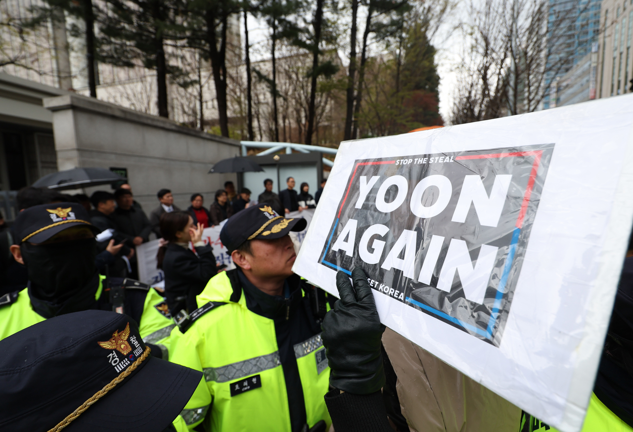 A protester is seen holding a “Yoon Again” sign in support of former President Yoon Suk Yeol in front of Seoul Central District Court on Monday, as Yoon’s criminal trial on charges of orchestrating an insurrection through declaring martial law Dec. 3 was taking place. (Yonhap)