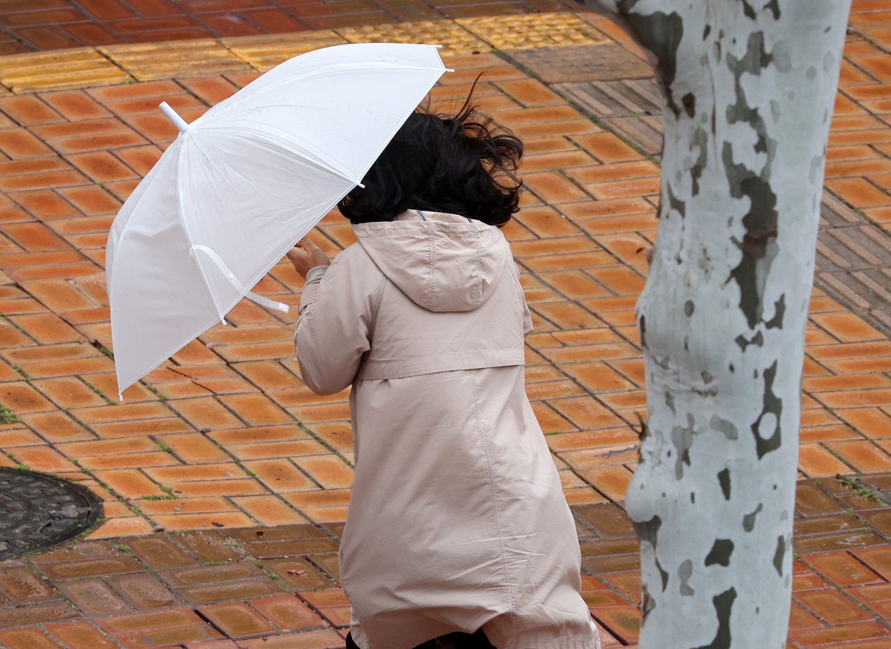 A pedestrian struggles to walk through the rain and strong winds in Gwangju on Monday. (Yonhap)