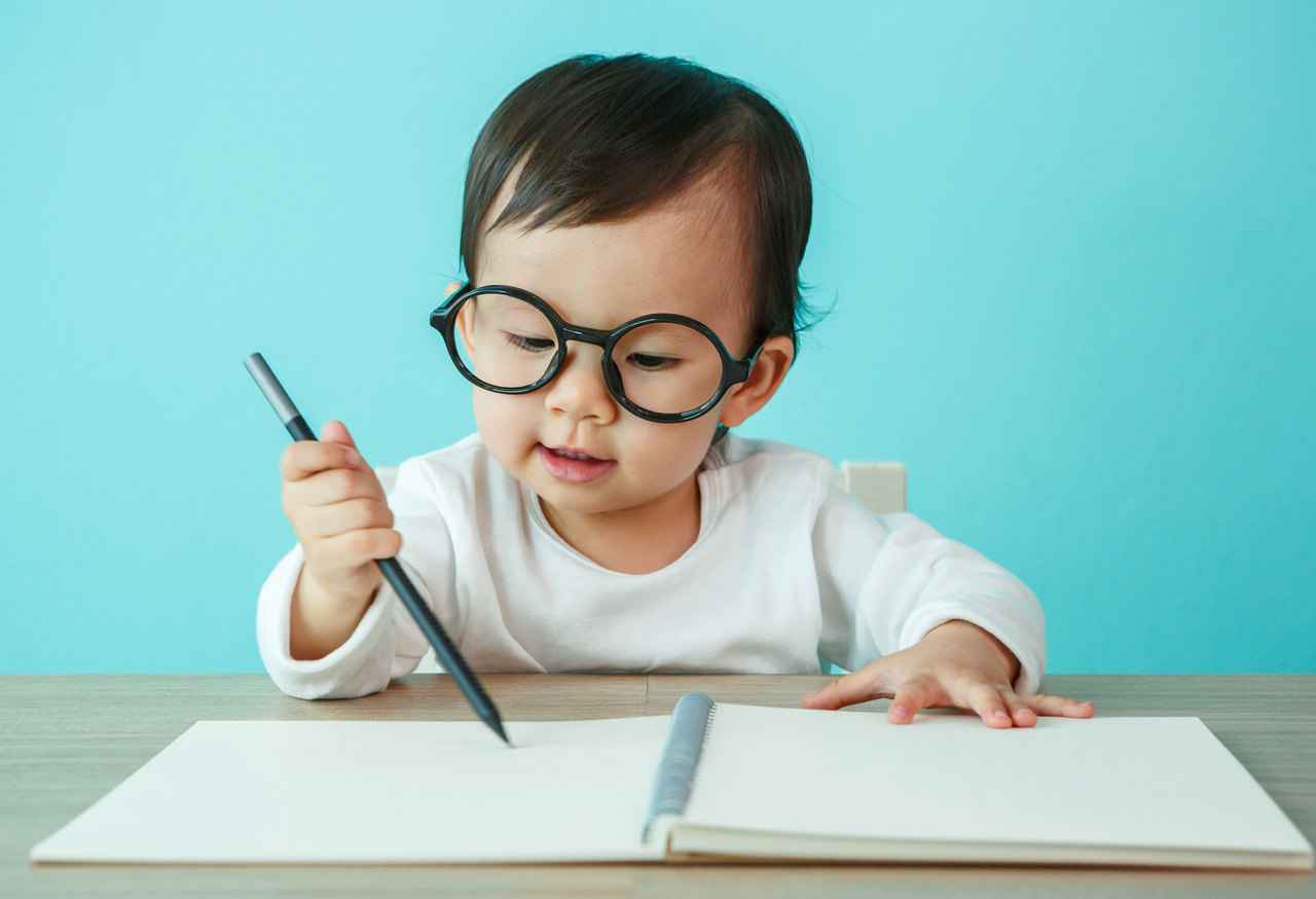Portrait of an adorable baby girl wearing glasses on the table (soft focus on the eyes)