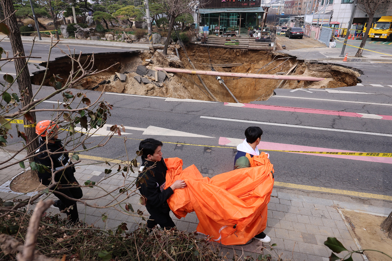 A 20-meter-wide, 18-meter-deep sinkhole is seen in front of Daemyung Elementary School in Gangdong-gu, Seoul on March 25. (Yonhap)