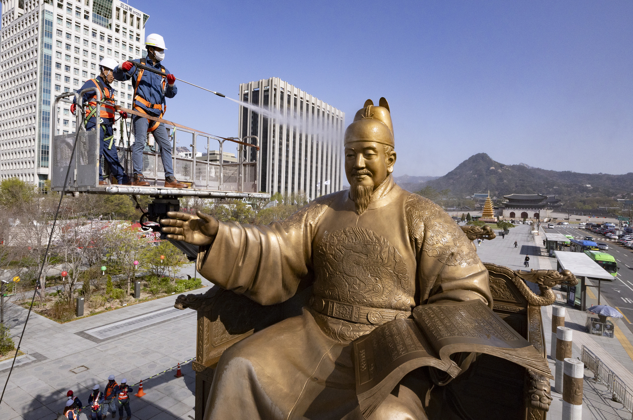 Professional cleaners washing dust off the statue (Yonhap)