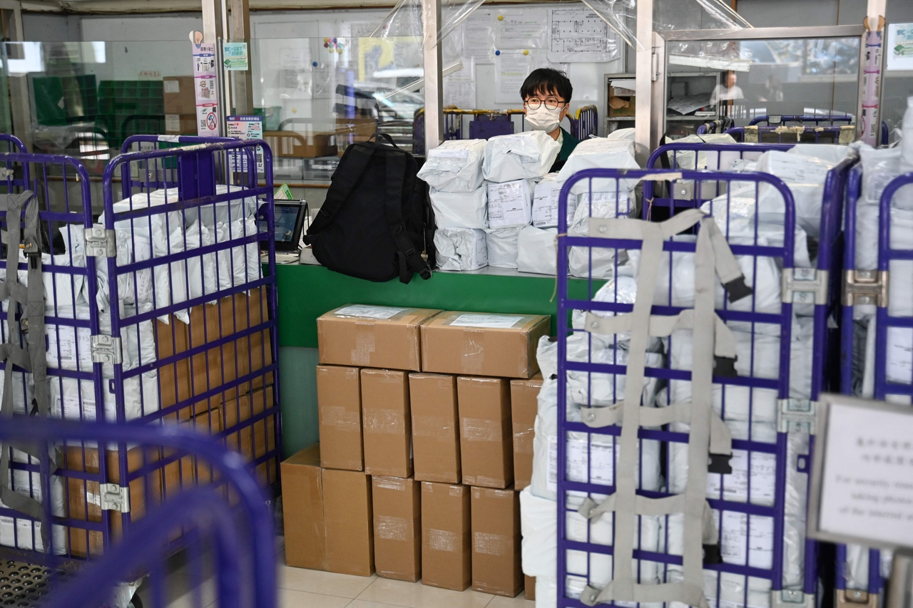 Stacked parcels are seen stacked in front of a counter as a Hongkong Post employee stands behind the window at a post office in Hong Kong on Wednesday. AFP-Yonhap