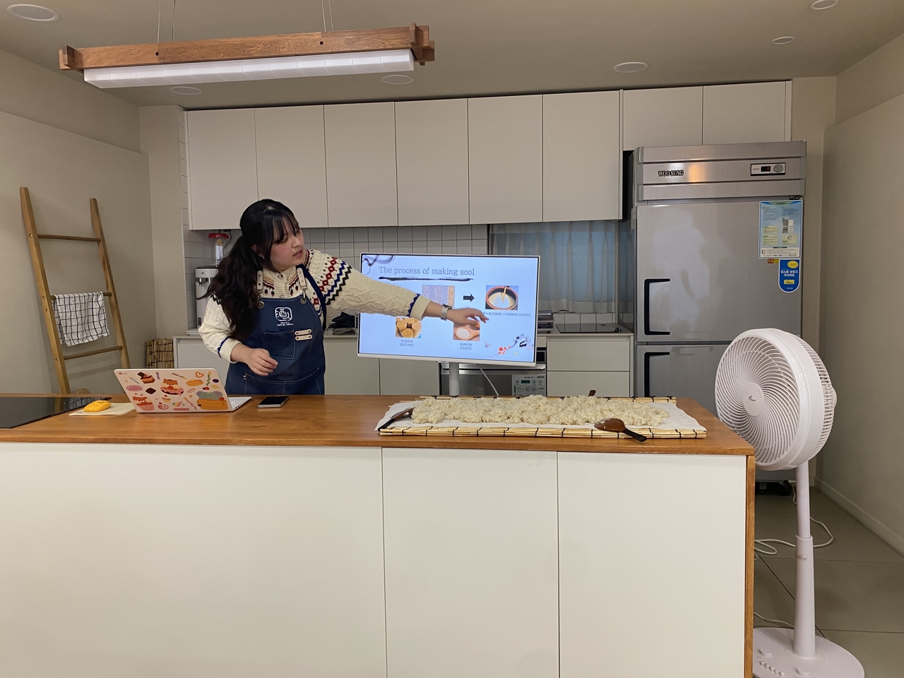 Instructor Kwon Hae-den of Suguk explains the makgeolli-making process as rice cools during the class on Monday. (Lim Jae-seong/The Korea Herald)