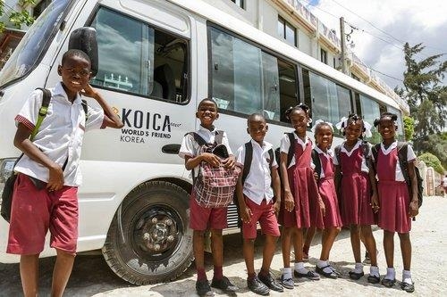 Haitian children pose in front of a school bus provided by the Korea International Cooperation Agency. (KOICA)
