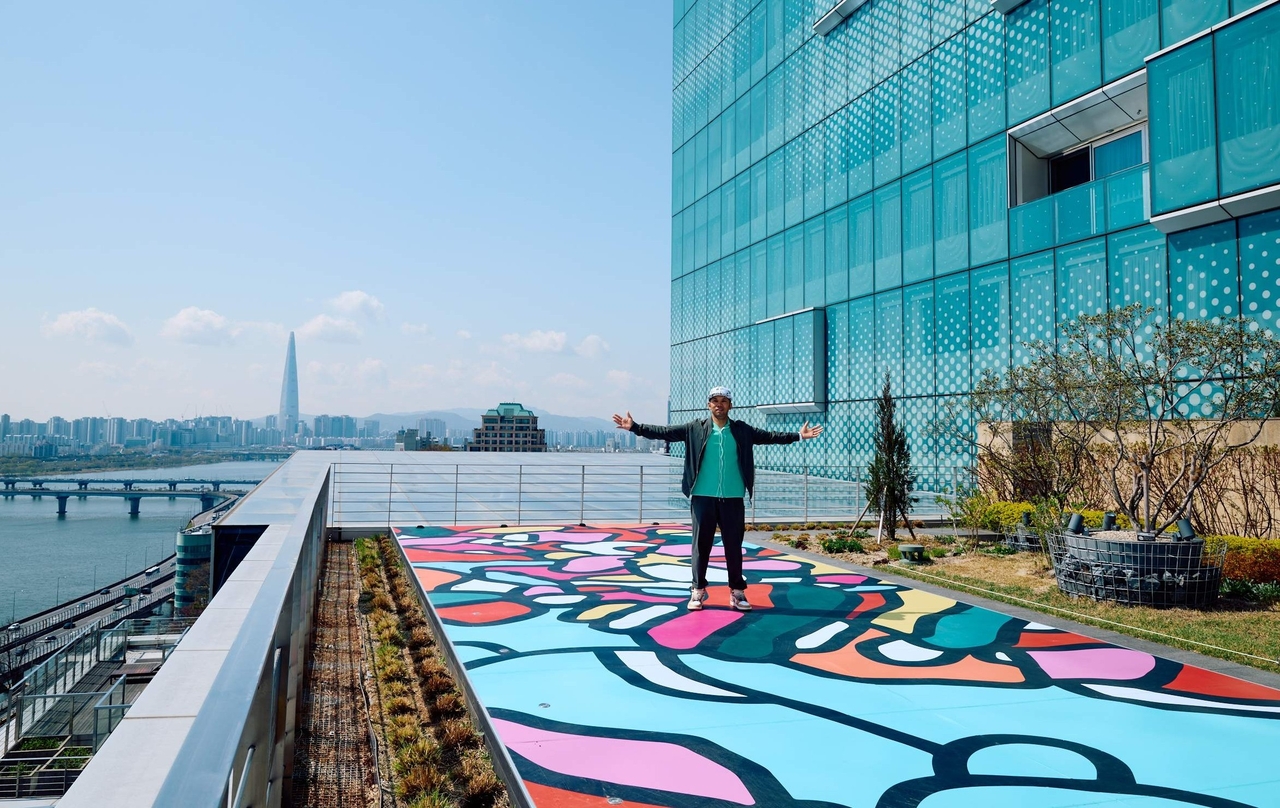 제이슨 아티엔자가 워커힐 스카이야드에 디자인한 작품 ‘엘리베이트 유어 바이브레이션(Elevate your vibration)’에서 포즈를 취하고 있다