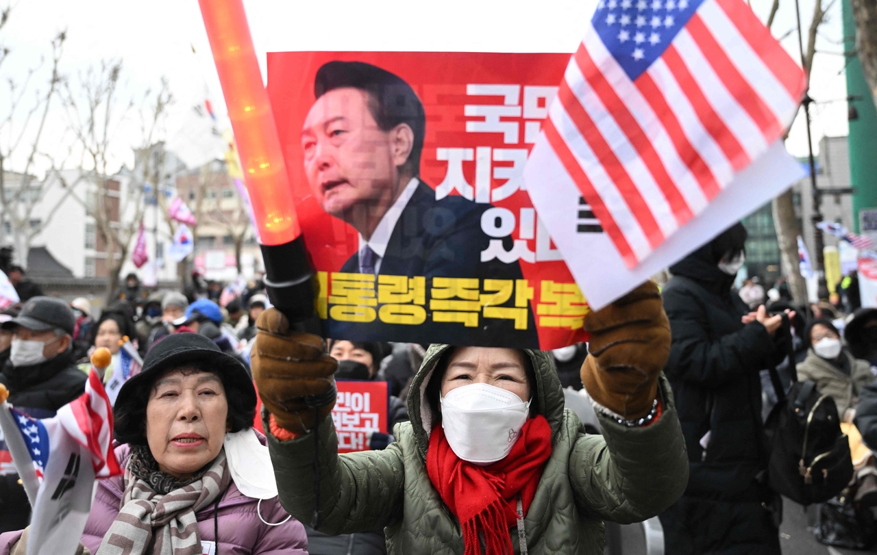 Supporters of ex-President Yoon Suk Yeol hold placards showing a picture of Yoon during a rally near the Constitutional Court in Seoul on Feb. 25, as Yoon is scheduled to attend his final impeachment hearing. (AFP-Yonhap)