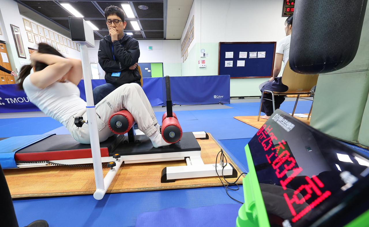 An applicant performs a situp test during the physical fitness assessment for the 2025 police officer exam, held Friday at the Incheon Metropolitan Police Agency’s training center in Incheon. (Yonhap)
