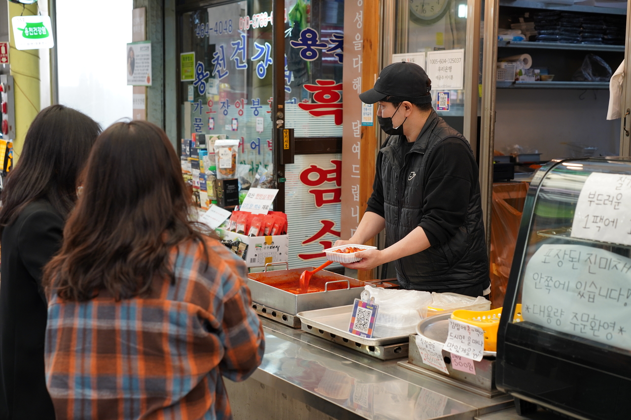 Customers await their tteokbokki order in front of Tailor Gimbap in Junggok Jeil Market in Gwangjin-gu, eastern Seoul. (Lee Si-jin/The Korea Herald)