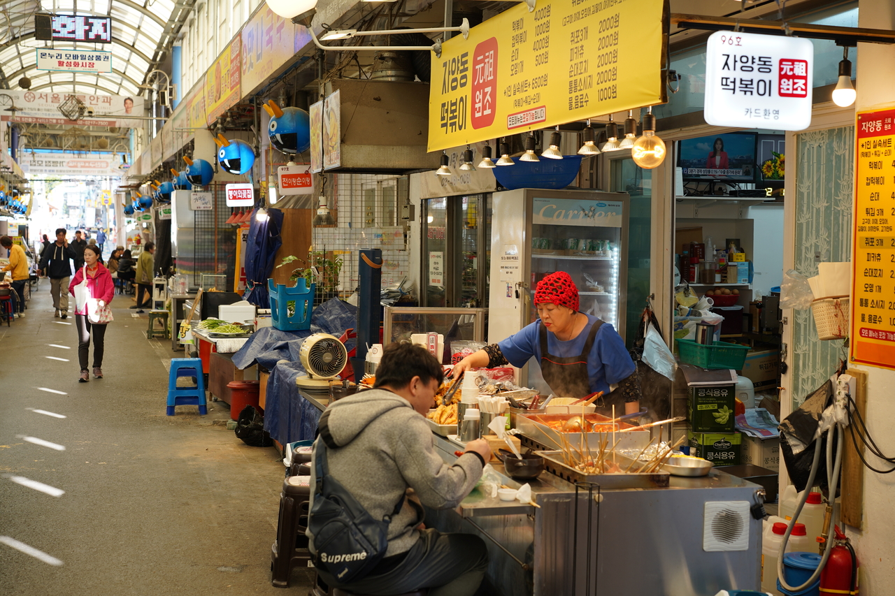 A visitor enjoys fish cakes at Jayangdong Tteokbokki in Junggok Jeil Market. (Lee Si-jin/The Korea Herald)