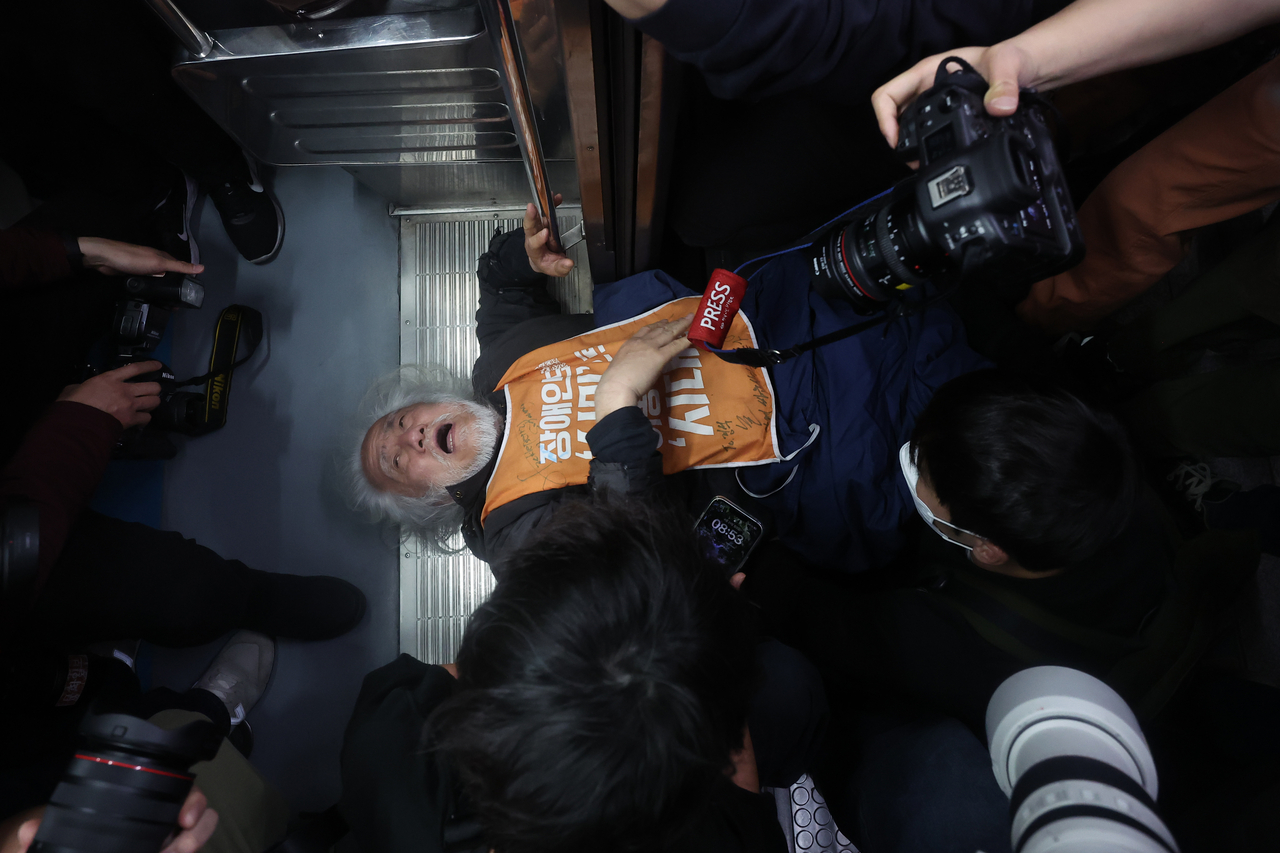 Park Kyoung-seok, head of Solidarity Against Disability Discrimination, lies at the entrance of a train after clashing with Seoul Metro officials during a subway-riding protest at Hyehwa Station on Subway Line No. 4 in Seoul on Monday. (Yonhap)