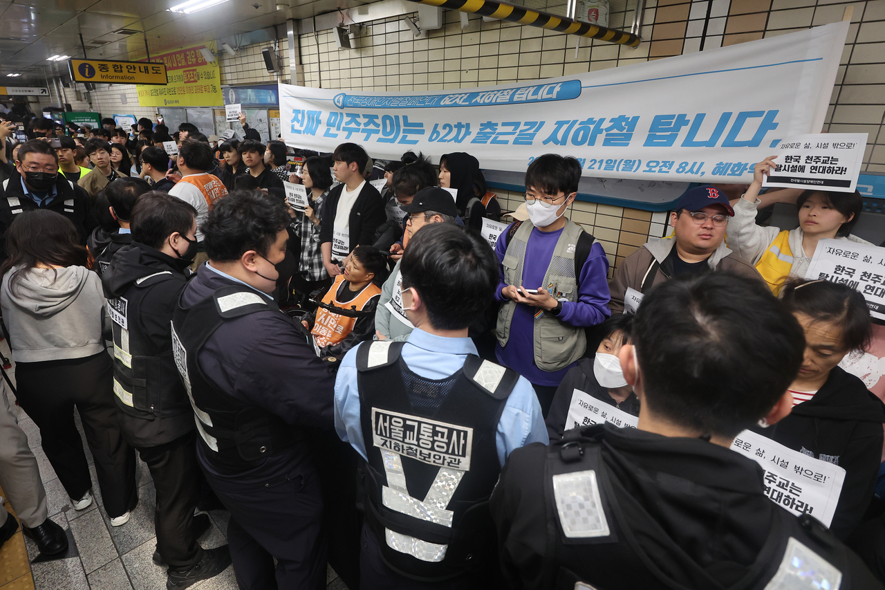 Solidarity Against Disability Discrimination protesters confront Seoul Metro officials during a subway-riding protest at Hyehwa Station on Subway Line No. 4 in Seoul on Monday. (Yonhap)