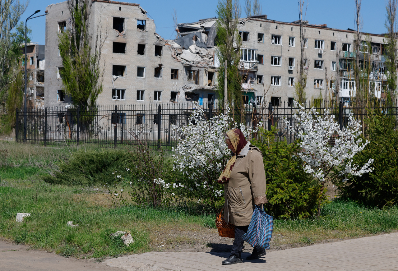 A woman walks from a church during Orthodox Easter celebrations, as an apartment building damaged in the course of Russia-Ukraine conflict is seen in the background, in Avdiivka, Donetsk region, Sunday.   Reuters-Yonhap