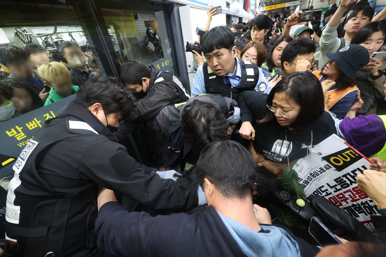 Solidarity Against Disability Discrimination protesters clash with Seoul Metro officials while attempting to board the subway at Hyehwa Station on Subway Line No. 4 in Seoul on Monday. (Yonhap)